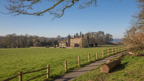 A view across a field, with a fence in the foreground, towards Newton House at Dinefwr, Carmarthenshire